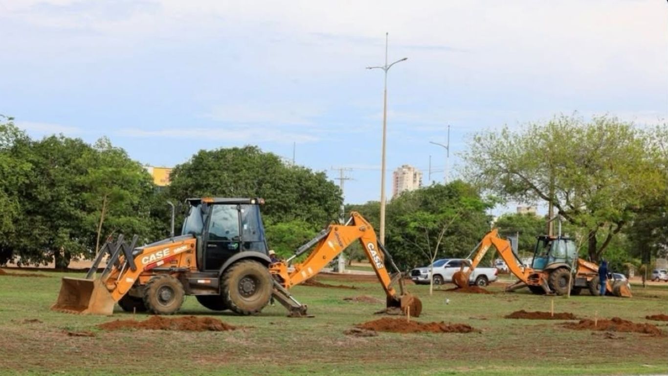 Máquinas escavadeiras realizando abertura de covas para o plantio de mudas em área verde de Palmas.