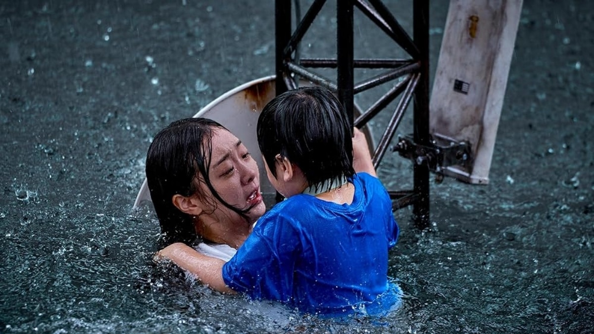 Cena emocionante de A Grande Inundação (Netflix 2025) com mãe (Kim Da-mi) abraçando desesperadamente o filho na água da inundação, sob chuva forte, representando o sacrifício materno no filme sul-coreano.