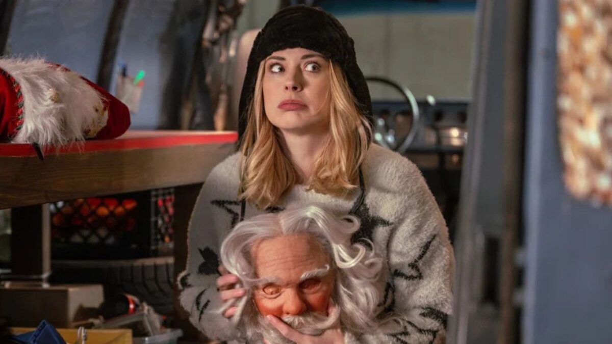 Cena do filme Meu Papai Noel Secreto (2025) mostra personagem feminina segurando a cabeça do Papai Noel em clima de mistério