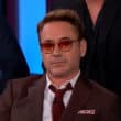 Ator de Hollywood usando óculos escuros e terno durante entrevista em estúdio de TV